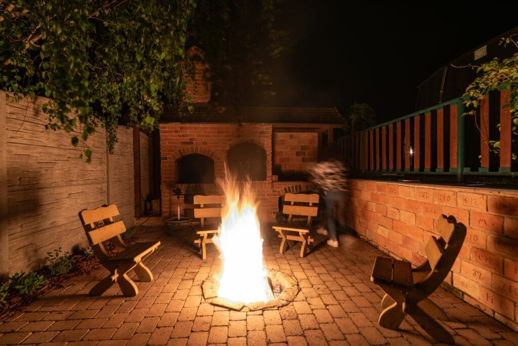 Dřevěná sudová sauna v zahradě Wellness Hříbek Resortu, doplněná sochou houby a květinami