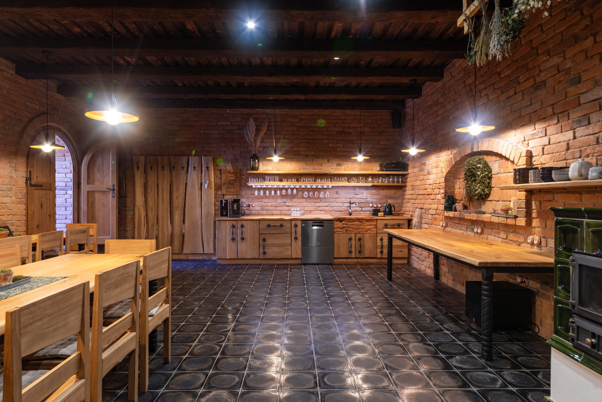 Stylové posezení ve vinném sklepě Wellness Hříbek – dřevěný stůl a židle na tmavé keramické dlažbě